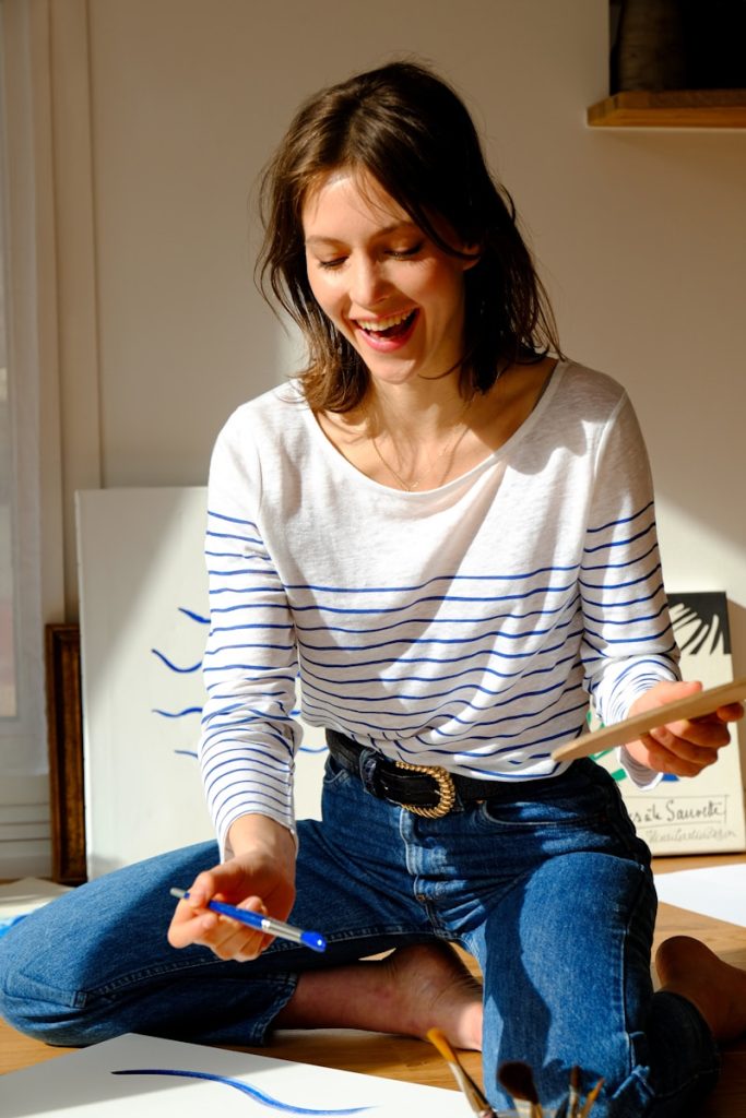 Maite Junquera en Ciudad de Madrid woman in white and black striped long sleeve shirt and blue denim jeans sitting on bed